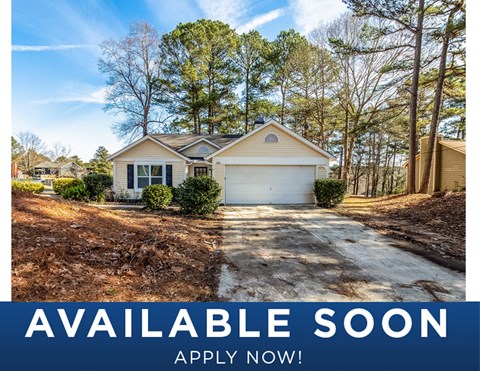 a home in the woods with a driveway and a garage door